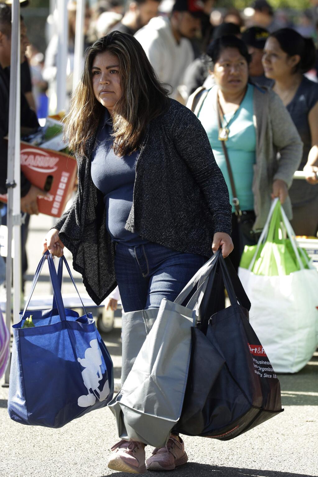 People gather items during a free food distribution for migrant workers evacuated because of the Kincade fire Thursday, Oct. 31, 2019, in Healdsburg, Calif. (AP Photo/Charlie Riedel)