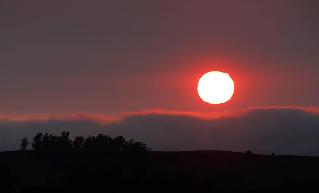 The sun sets behind layers of fog and haze, a result of the recent Northern California wildfires, above the hills west of Petaluma, California, on Wednesday, Aug. 8, 2018. Sonoma County has had a number of Spare the Air alerts during the summer fire season. (ALVIN JORNADA/ PD)