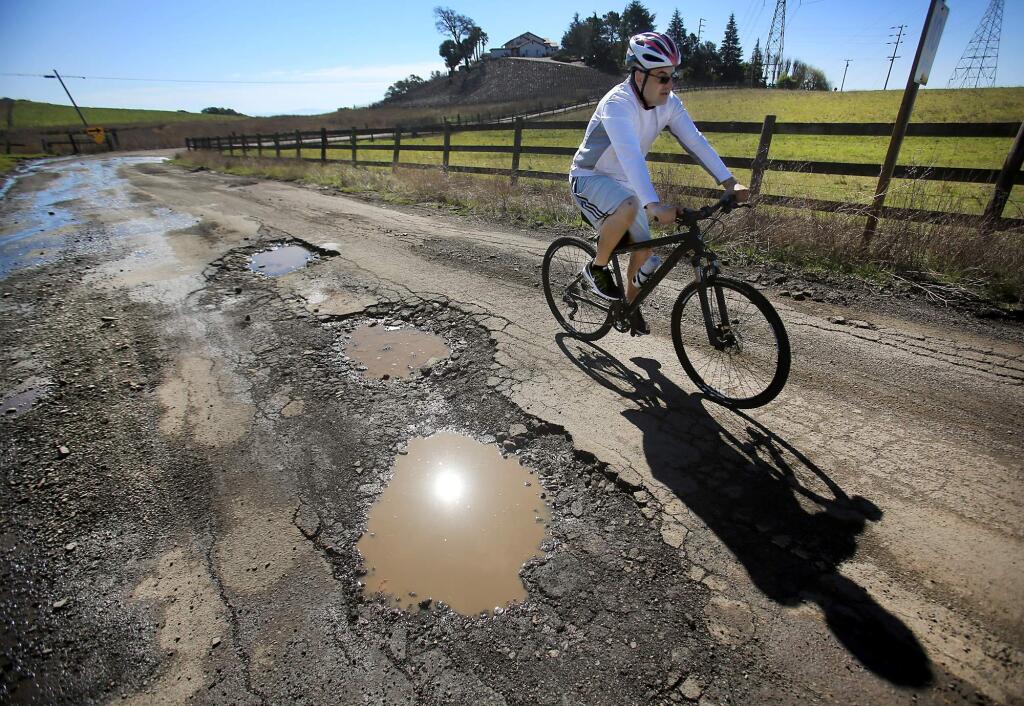 Sergio Vasquez of Petaluma navigates the pothole strewn Sonoma Mountain road above Petaluma, Thursday March 2, 2017. Record punishing rain has played havoc with area road infrastructure this winter some of which was already in disrepair. (Kent Porter / The Press Democrat) 2017
