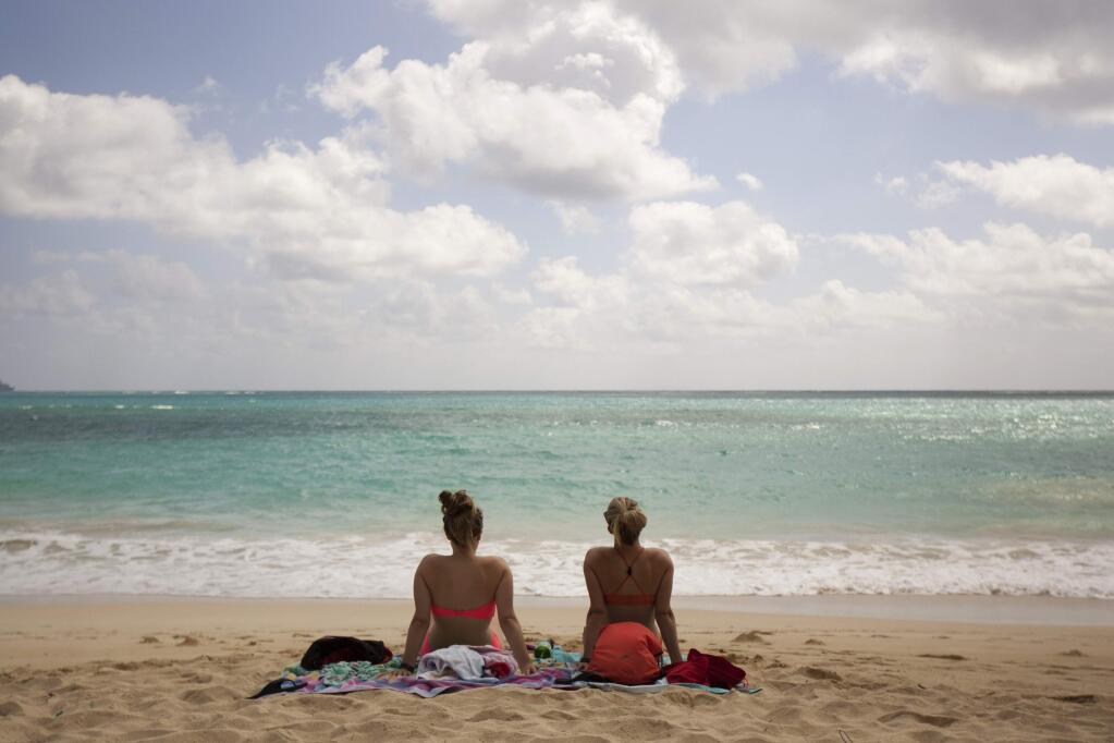 In this May 19, 2015 photo, Ali Junell, of Portland, Ore., left, and Kristen Carmichael, of Los Angeles, sit on the beach at Waimanalo Bay Beach Park in Waimanalo, Hawaii. The beach was listed as No. 1 on the 2015 list of best beaches, a list compiled annually by Florida International University Professor Stephen Leatherman, also known as Dr. Beach. (AP Photo/Caleb Jones)