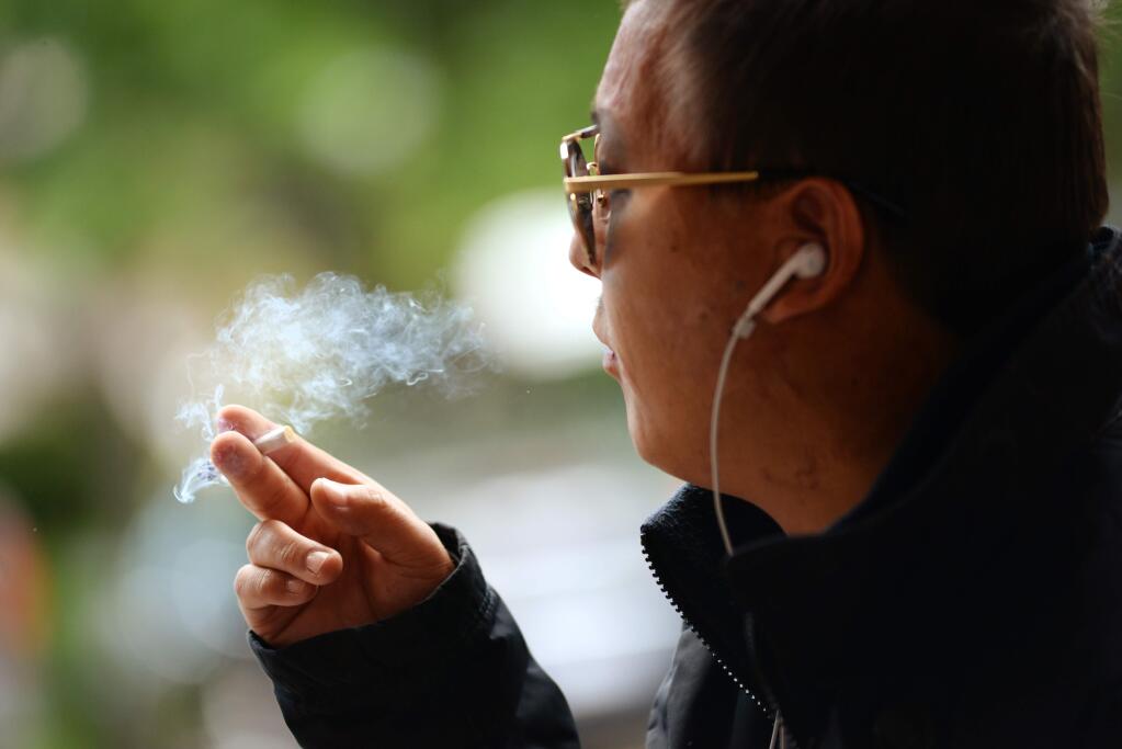 Jack Namji, originally from Mongolia but now a Bay Area resident, takes a smoking break next to the Town Square sports bar on First Street East in downtown Sonoma on May 20, 2016. (Erik Castro / for The Press Democrat)