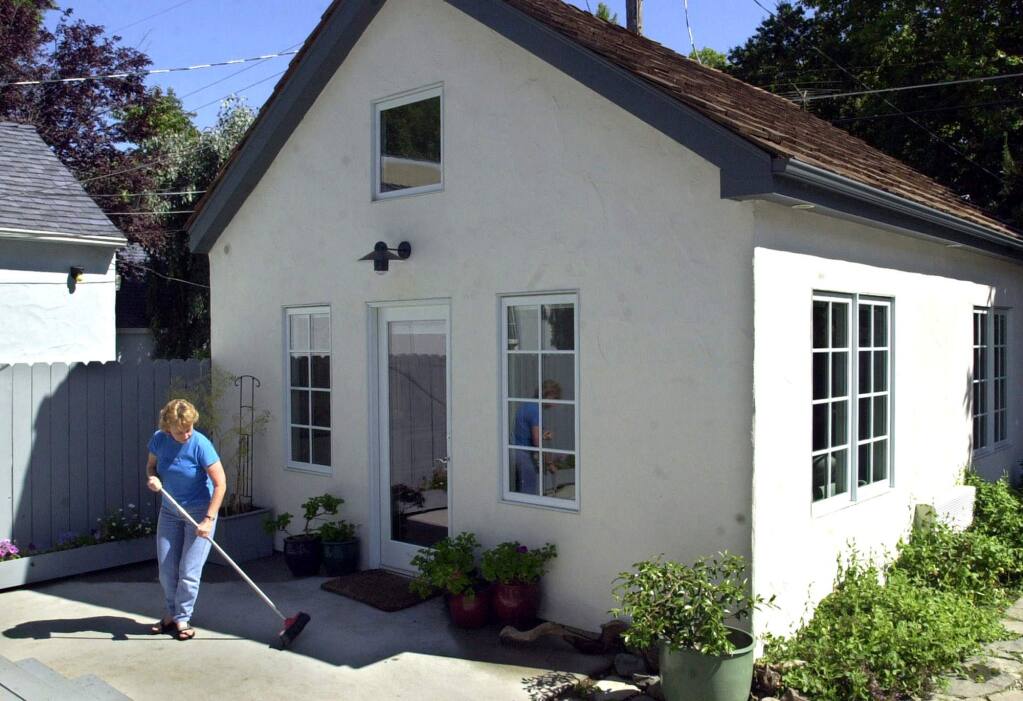Christine Minnehan sweeps up in front of the granny flat in the backyard of her Sacramento home. (RICH PEDRONCELLI / Associated Press, 2002)