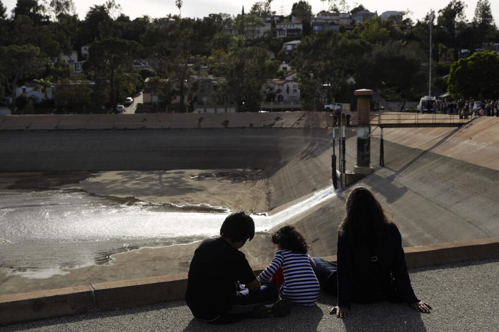 Stephanie Bartron, right, and her two children, Dashiell, left, and Marlowe watch as water flows into the Silver Lake Reservoir Complex, Tuesday, April 25, 2017, in Los Angeles. Officials on Tuesday began the process of refilling the 96-acre Silver Lake and Ivanhoe reservoirs, which once held drinking water and was a landmark in the arty, upscale neighborhood. (AP Photo/Jae C. Hong)