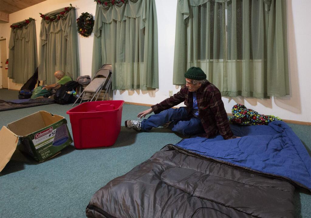 Having made up his bed, John Fassio takes off his shoes before tucking in for the night at the Sonoma Alliance Church on Watmaugh Road. (Photo by Robbi Pengelly/Index-Tribune)