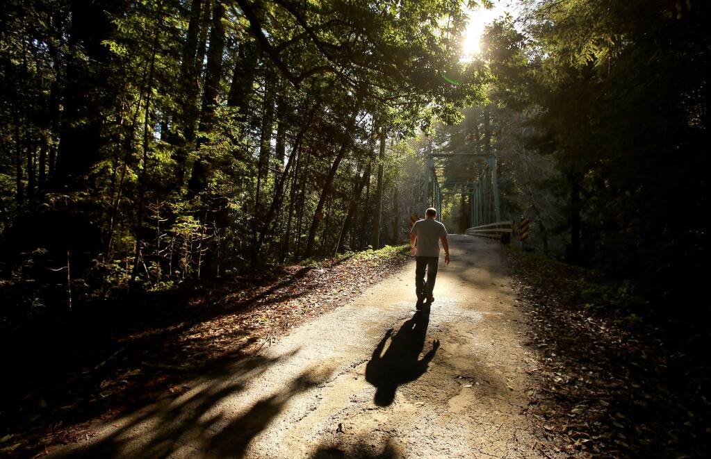 Mark Hancock, a publicity coordinator at Gualala Arts, walks along Gualala River Road, near the north fork of the Gualala River, in this November 2014 file photo. Nearly 30,000 acres of property are being sold by Gualala Redwoods, Inc.(Christopher Chung/ The Press Democrat)