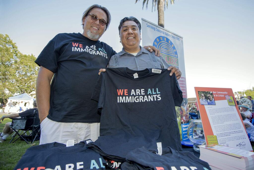 La Luz board president Marcello de Freitas (left) and executive director Juan Hernandez at Tuesday's farmers market on the Plaza giving away a t-shirt with each donation of $20. (Photo by Robbi Pengelly/Index-Tribune)