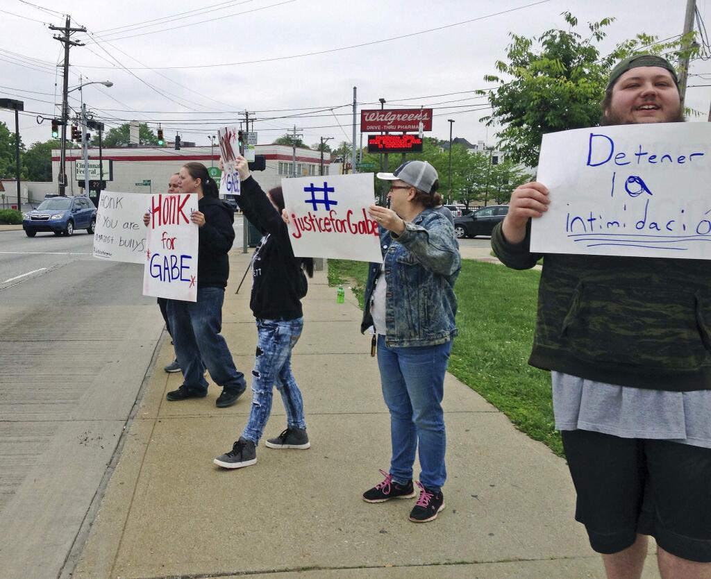 Parents and other demonstrators hold signs against bullying and in memory of Gabriel Taye, an 8-year-old boy who killed himself in January 2017 two days after being knocked unconscious by another Carson School student, on Friday, May 12, 2017, outside the elementary school in Cincinnati. Cincinnati Public Schools released a 24-minute surveillance video Friday that appears to show Gabriel trying to shake the hand of a boy who had hit another child, and then collapsing to the floor after being pushed into a wall at the entrance of a boys' bathroom. (AP Photo/Lisa Cornwell)