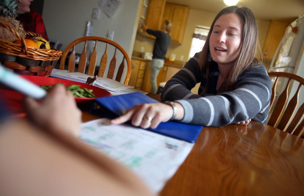 Former program director Emily Mann helps a child in foster care with a word search at Sonoma County Children's Village in Santa Rosa in February 2014. (Christopher Chung/ The Press Democrat)