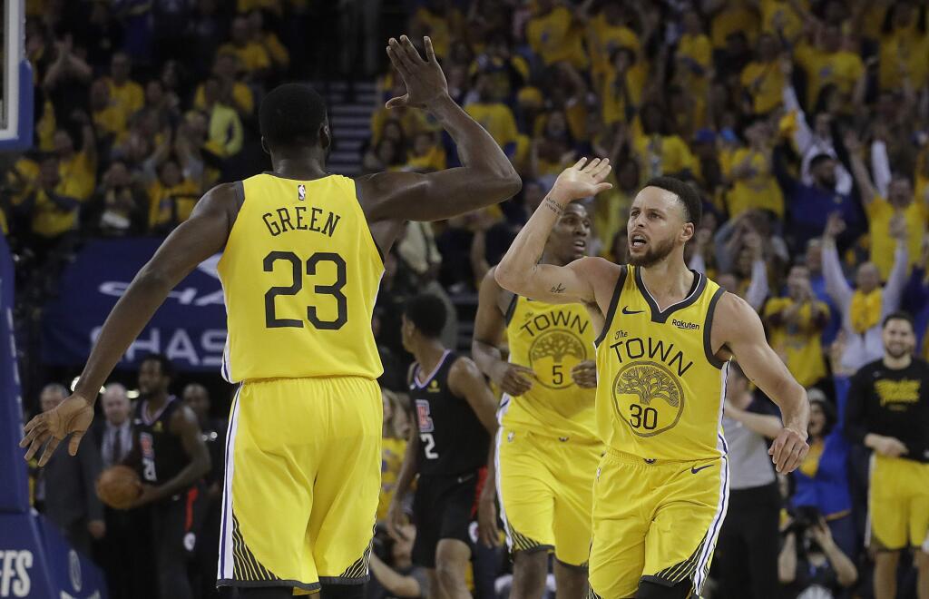 Golden State Warriors forward Draymond Green celebrates with guard Stephen Curry during the first half of Game 2 of a first-round playoff series against the Los Angeles Clippers in Oakland, Monday, April 15, 2019. (AP Photo/Jeff Chiu)