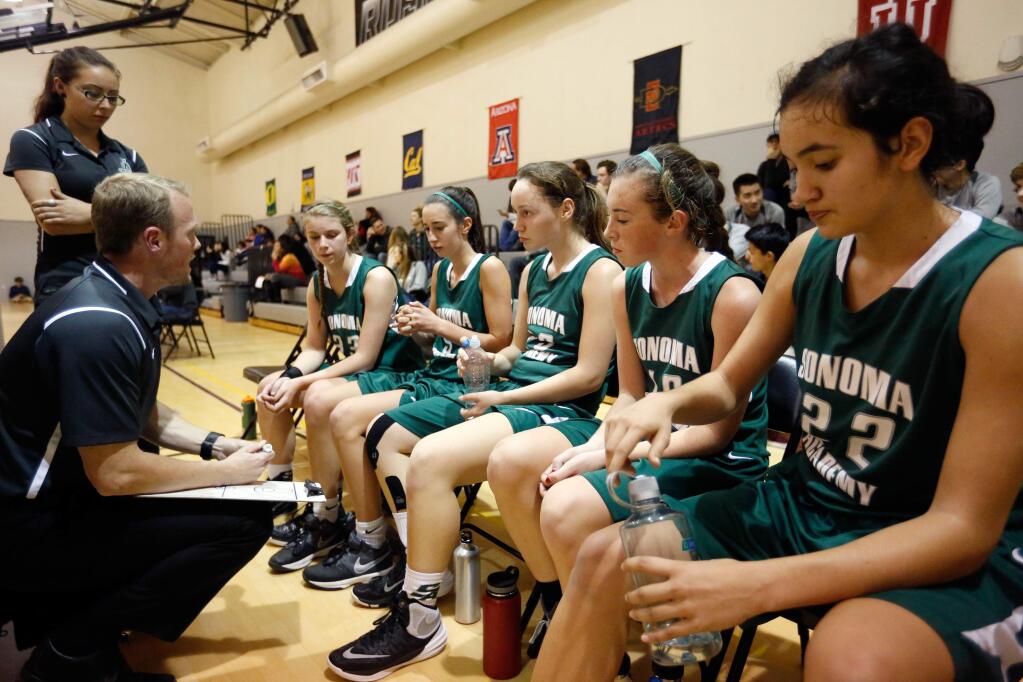 Sonoma Academy players, from right, Clara Spars (22), right, Tristen Sherley (10), Stacey Olson (23), Gabrielle Tukman (5), and Lauren Reed (33) huddle with head coach Kevin Christensen, kneeling at left, and assistant coach Jen Tsurumoto during a time out in a girls varsity basketball game between Sonoma Academy and Roseland University Prep in Santa Rosa, California on Tuesday, January 26, 2016. (Alvin Jornada / The Press Democrat)
