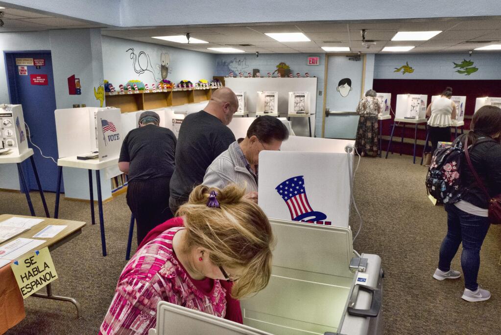 Voters place their votes at a polling station inside the library at the Robert F. Kennedy Elementary School after casting his ballot in Los Angeles on Tuesday, June 5, 2018. California's primary election will set the stage for November races for governor, Congress and the Legislature, but it will also test whether the state's vanishing Republicans have enough remaining influence to avoid another shutout at the statewide polls. (AP Photo/Richard Vogel)