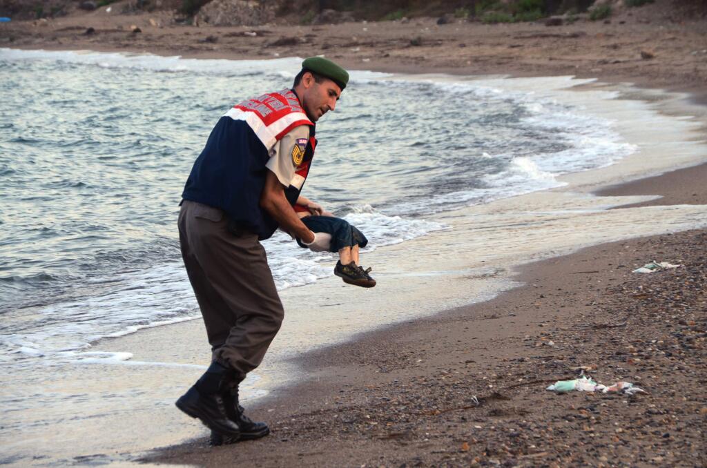 A paramilitary police officer carries the lifeless body of a migrant child after a number of migrants died and a smaller number were reported missing after boats carrying them to the Greek island of Kos capsized near the Turkish resort of Bodrum early Wednesday. (DHA / Associated Press)