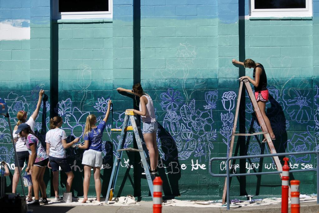 Members of the St. Vincent de Paul High School's Art Angels club paint a mural on the wall of the Cavanagh Recreation Center on Sunday, September 25, 2016 in Petaluma, California . (BETH SCHLANKER/ The Press Democrat)