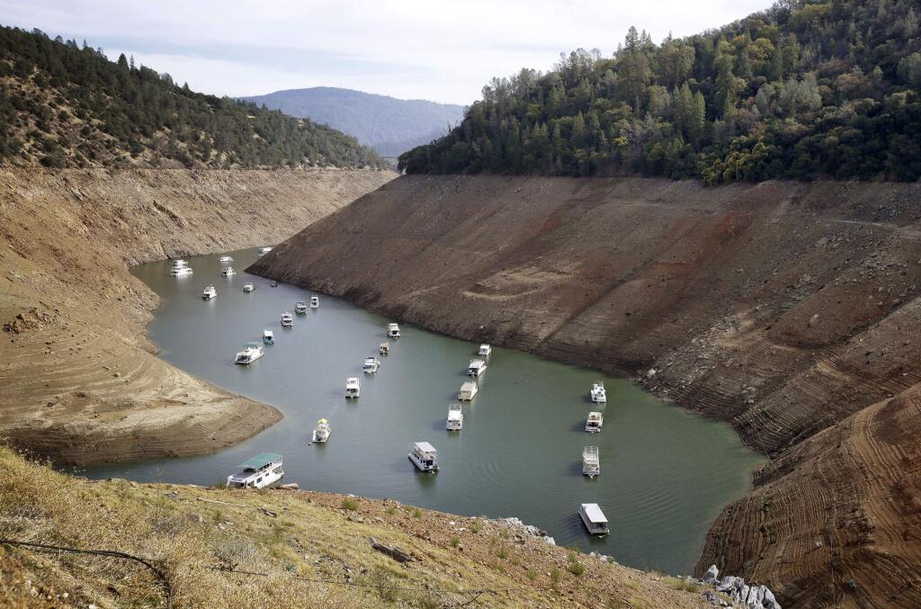 FILE - In this Thursday, Oct. 30, 2014, file photo, houseboats float in the drought-lowered waters of Oroville Lake near Oroville, Calif. Voters will decide whether California borrows nearly $9 billion for water infrastructure projects in the state where its scarcity often pits city dwellers, farmers, anglers and environmentalists against one another. Proposition 3 on the ballot Tuesday, Nov. 6, 2018 would direct the money to storage and dam repairs, watershed and fisheries improvements, and habitat protection and restoration. (AP Photo/Rich Pedroncelli, File)