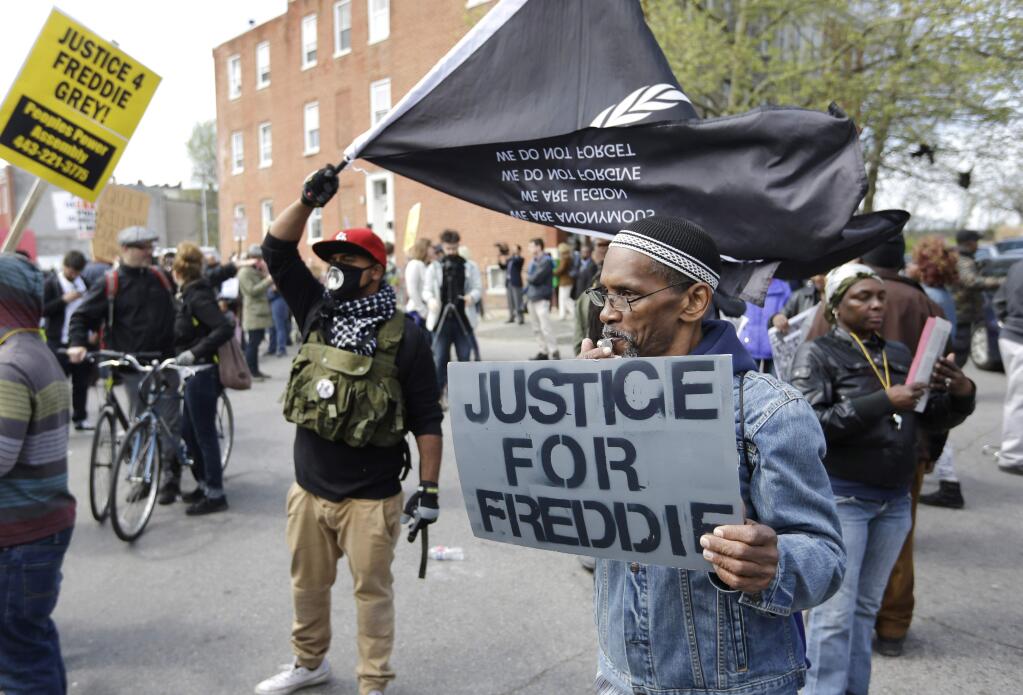 Protestors gather outside the Baltimore Police Department's Western District police station before a match for Freddie Gray, Saturday, April 25, 2015, in Baltimore. Gray died from spinal injuries about a week after he was arrested and transported in a police van. (AP Photo/Patrick Semansky)
