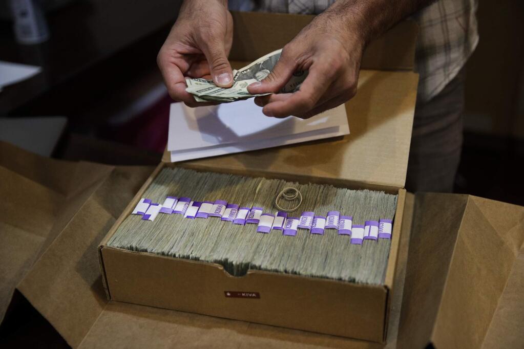FILE - In this June 27, 2017 file photo, the proprietor of a medical marijuana dispensary prepares his monthly tax payment, over $40,000 in cash, at his Los Angeles store. Congress on Wednesday, Feb. 13, 2019, was urged to fully open the doors of the nation's banking system to the legal marijuana industry, a change that supporters say would reduce the risk of crime and resolve a litany of problems for pot companies from paying taxes to getting a loan. (AP Photo/Jae C. Hong, File)