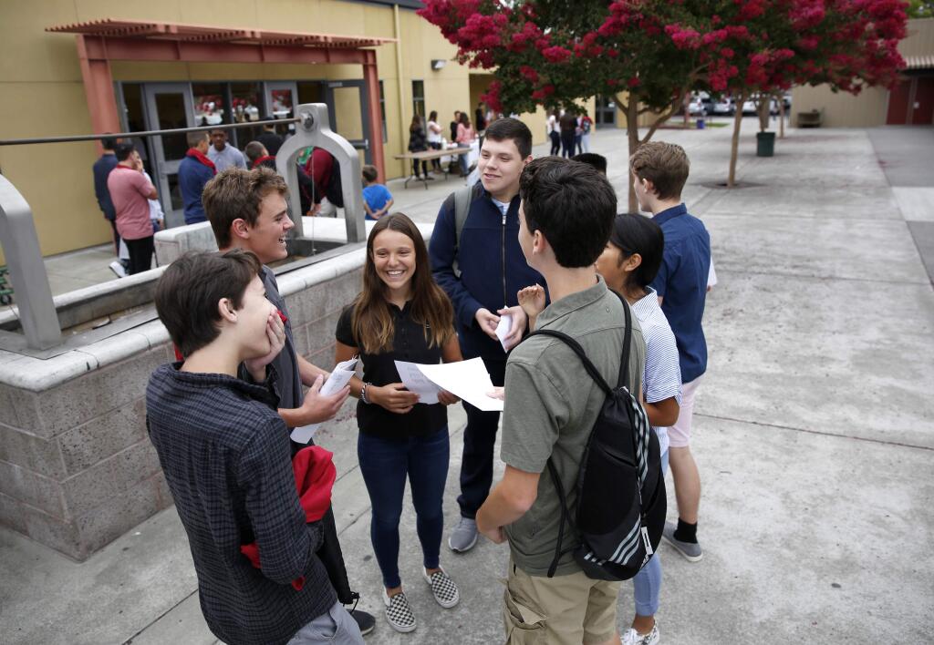 Students including Abby Salnas, 15, center, Patrick Cvitanovic, 15, center left, and Eddie Calderon, 15, center rear, talk together after registering for classes at Cardinal Newman High School in Santa Rosa on Tuesday, August 14, 2018. (Beth Schlanker/ The Press Democrat)