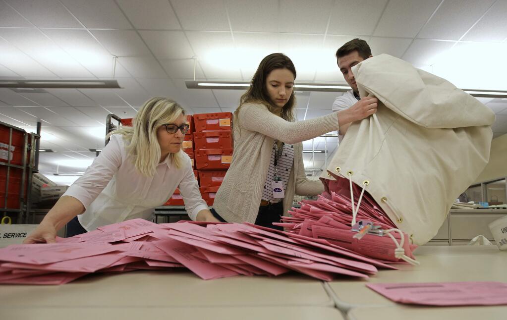 Election workers Heidi McGettigan, left, Margaret Wohlford, center, and David Jensen, unload a bag of ballots brought in a from a polling precinct to the Sacramento County Registrar of Voters office, Tuesday, June 5, 2018, in Sacramento, Calif. (AP Photo/Rich Pedroncelli)