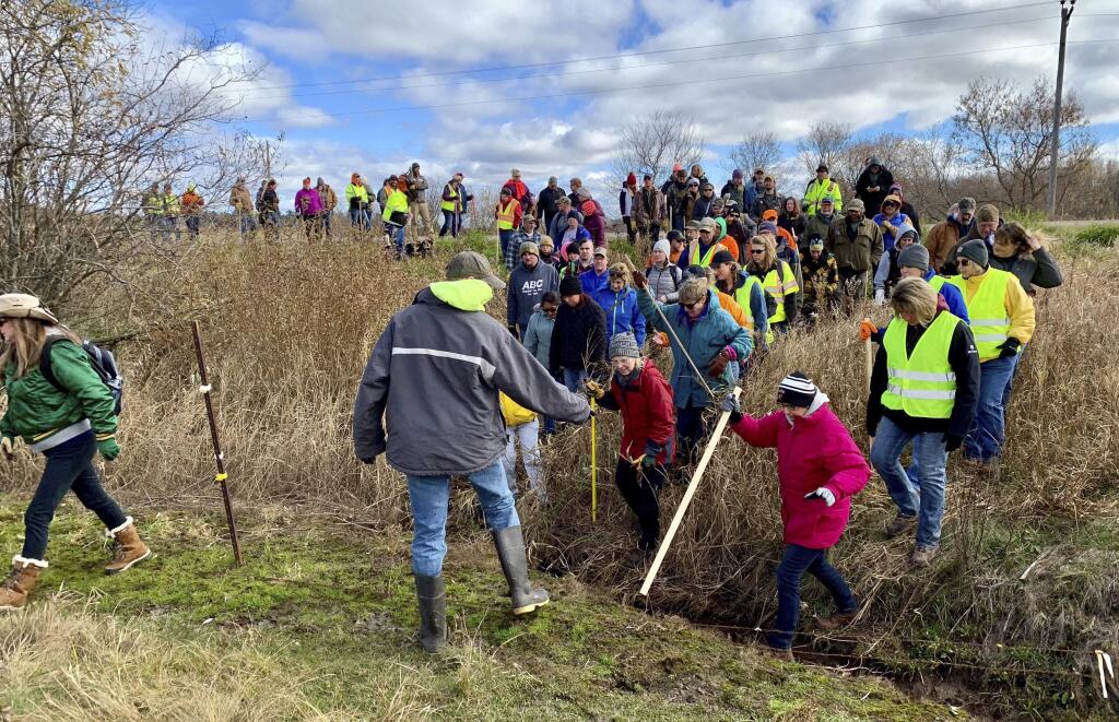FILE - In this Oct. 23, 2018, file photo, volunteers cross a creek and barbed wire near Barron, Wis., on their way to a ground search for 13-year-old Jayme Closs who was discovered missing Oct. 15 after her parents were found fatally shot at their home. The Barron County Sheriff's Department said on its Facebook page that that the teenager Closs has been located Thursday, Jan. 10, 2019, and that a suspect was taken into custody. (AP Photo/Jeff Baenen, File)