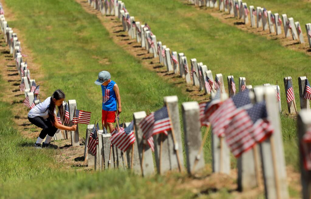 Amaris Gonzalez, 9, and her brother Angel, 5, add a flag to one of the nearly 6,000 graves of veterans at the Yountville Veteran's Home Cemetery on Memorial Day. (photo by John Burgess/The Press Democrat)