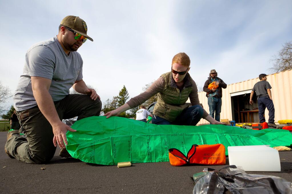 Sonoma County Regional Parks park ranger Beth Wyatt, center, and maintenance worker/certified arborist Terrence Erickson work together to repack a practice fire shelter, during a wildland firefighting orientation class for employees of Sonoma County Regional Parks and other public agencies at the SRJC Public Safety Training Center in Windsor, California, on Wednesday, January 29, 2020. (Alvin Jornada / The Press Democrat)
