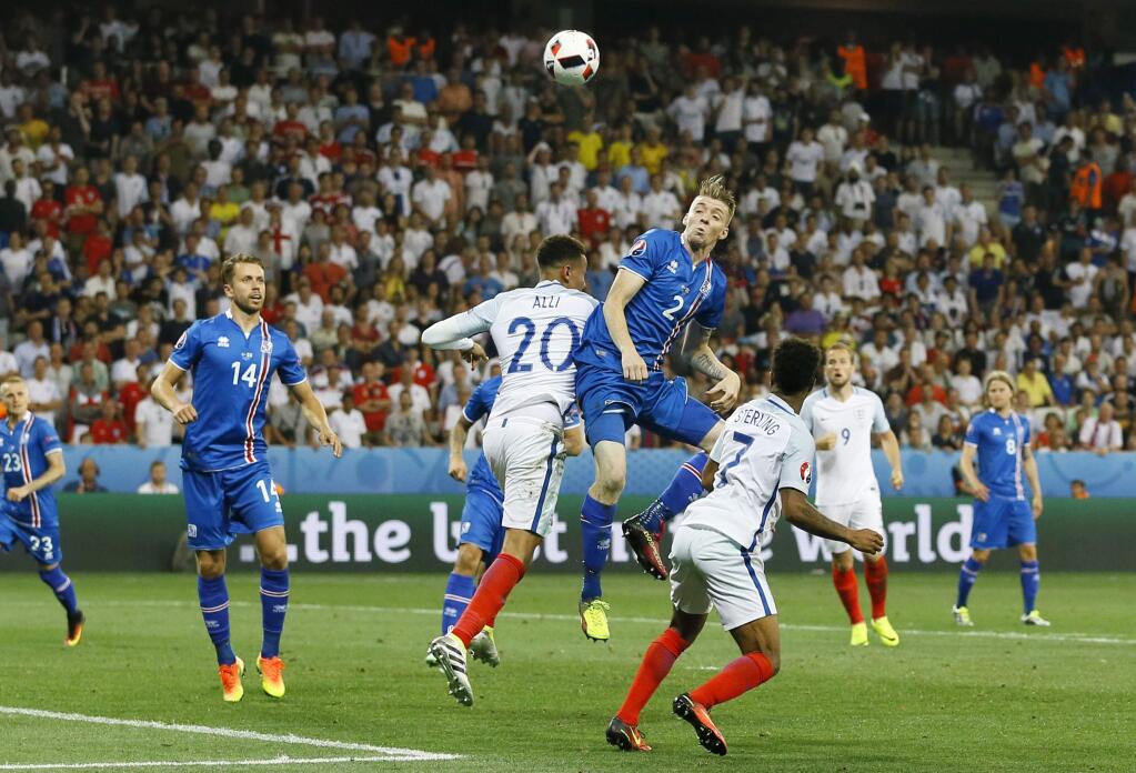 Iceland's Birkir Saevarsson, center right, jumps for the ball with England's Dele Alli during the Euro 2016 round of 16 soccer match between England and Iceland, at the Allianz Riviera stadium in Nice, France, Monday, June 27, 2016. (AP Photo/Kirsty Wigglesworth)