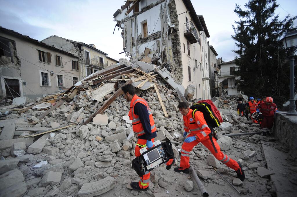 Rescuers search a crumbled building in Arcuata del Tronto, central Italy, where a 6.1 earthquake struck just after 3:30 a.m., Wednesday, Aug. 24, 2016. The quake was felt across a broad section of central Italy, including the capital Rome where people in homes in the historic center felt a long swaying followed by aftershocks. (AP Photo/Sandro Perozzi)
