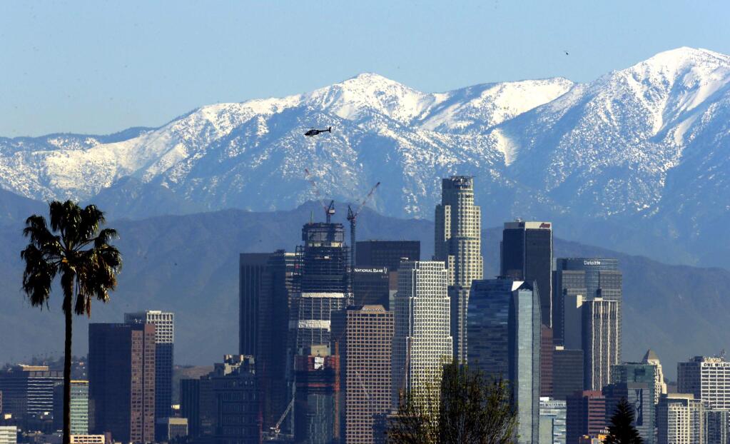 File - In this Jan. 12, 2016 file photo, the snow-capped San Gabriel Mountains stand as a backdrop to the downtown Los Angeles skyline. An initiative that seeks to split California into three states is projected to qualify for the state's November 2018 ballot. The latest proposal for splitting up the Golden State would create the states of Northern California, Southern California and a narrow central coast strip retaining the name California. Even if voters approve the initiative an actual split would still require the approval of the state Legislature and Congress. (AP Photo/Nick Ut, File)