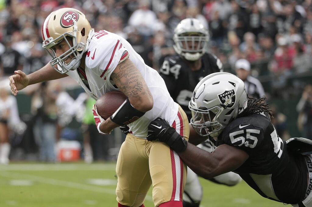 San Francisco 49ers quarterback Colin Kaepernick, left, is tackled by Oakland Raiders outside linebacker Sio Moore (55) during the first quarter of an NFL football game in Oakland, Calif., Sunday, Dec. 7, 2014. (AP Photo/Marcio Jose Sanchez)
