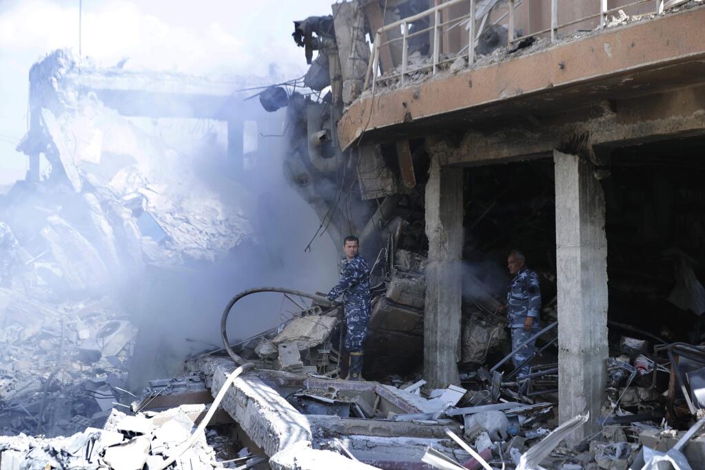 Firefighrers extinguish smoke that rises from the damage of the Syrian Scientific Research Center, which was attacked by U.S., British and French military strikes to punish President Bashar Assad for suspected chemical attack against civilians. (HASSAN AMMAR / Associated Press)