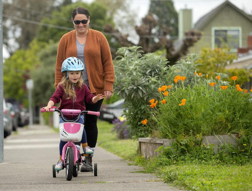 Ava Wadlow and her mother, Melissa, tried to learn how to ride without training wheels, but decided to put them back on for a ride through their Santa Rosa neighborhood. (John Burgess/The Press Democrat)