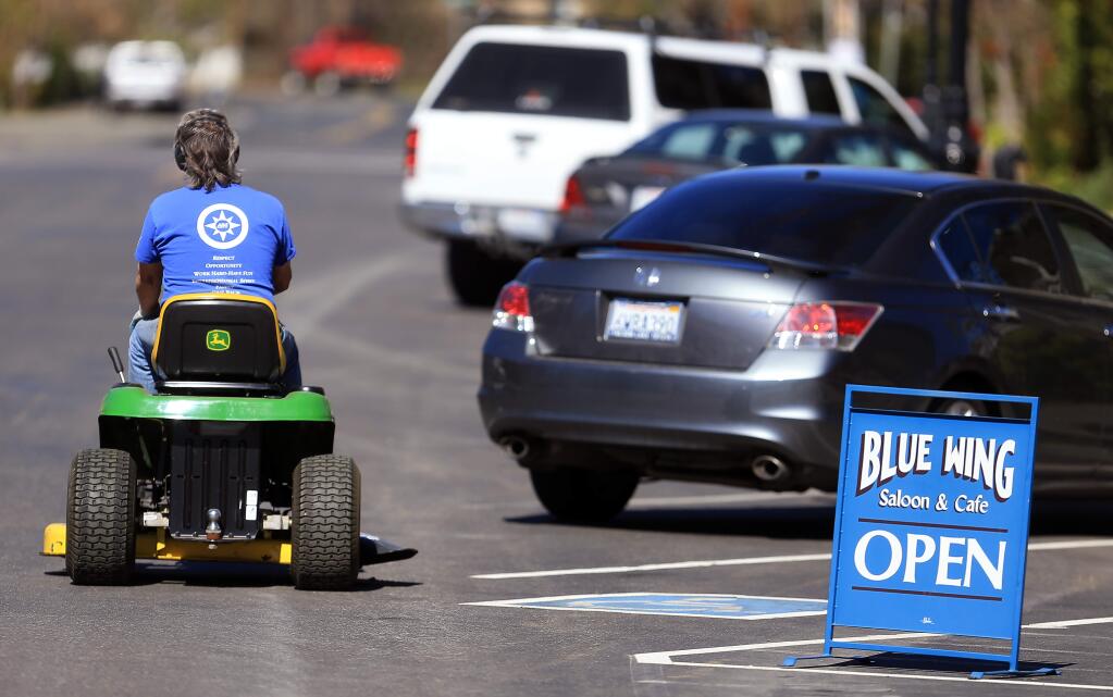 In Upper Lake, Buddy, who did not want last name used, rolls his lawnmower down main street to mow a friend's lawn, Friday March 6, 2015. (Kent Porter / Press Democrat)