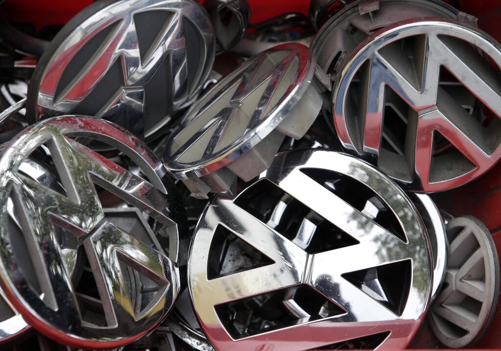 FILE - In this Sept. 23, 2015 file photo, company logos of the German car manufacturer Volkswagen sit in a box at a scrap yard in Berlin, Germany. (AP Photo/Michael Sohn, File)