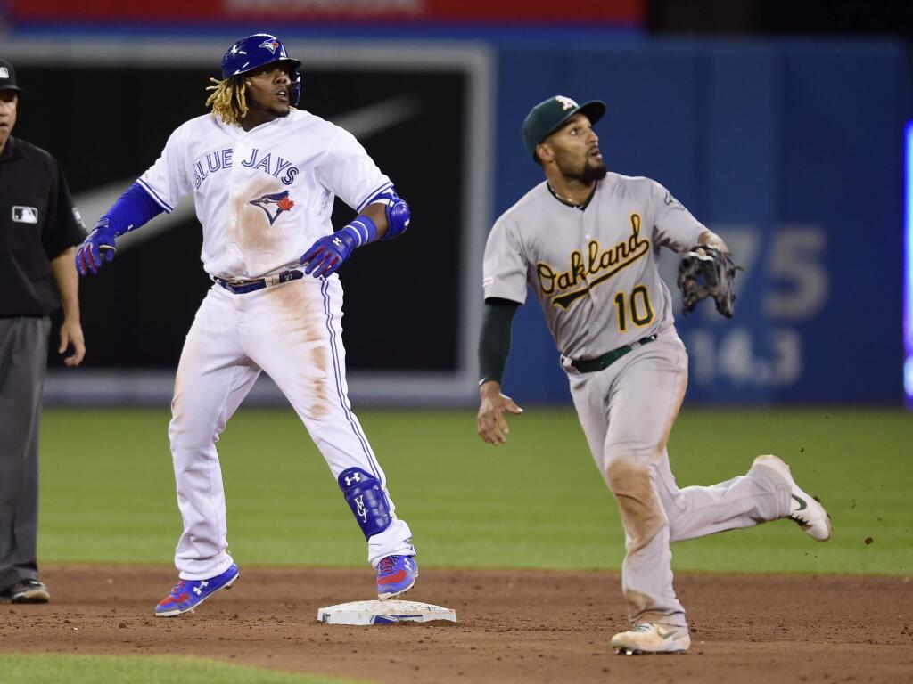 Toronto Blue Jays' Vladimir Guerrero Jr., front left, is safe at second on a double as Oakland Athletics shortstop Marcus Semien (10) looks on during ninth-inning baseball game action in Toronto, Friday, April 26, 2019. (Frank Gunn/The Canadian Press via AP)