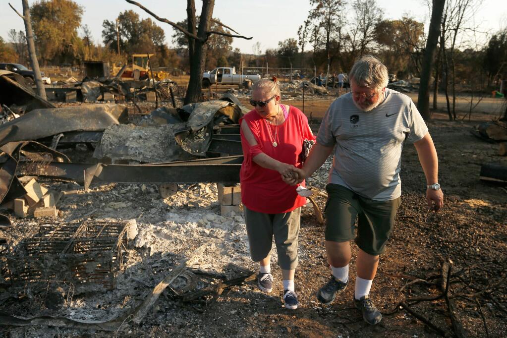 Matthew and Karen Porter hold hands as they survey the remains of their home for the first time after it was destroyed by the Clayton Fire, in Lower Lake, California on Friday, August 19, 2016. Mr. Porter is the armourer for the US Olympic fencing team and was in Rio de Janiero when the Clayton Fire destroyed his home and business. (Alvin Jornada / The Press Democrat)