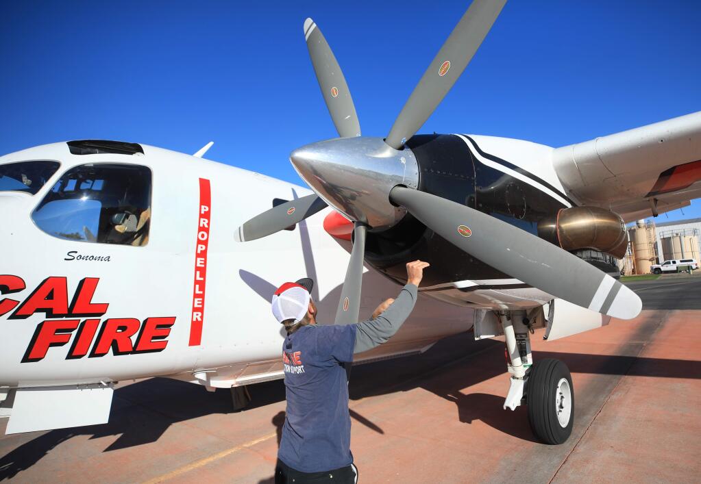 Cal Fire relief Andrew Rhynard turns the prop on an S2-T air tanker to force heat from the engine, Monday, Nov. 25, 2019 at the Sonoma Air Attack Base in Santa Rosa. (Kent Porter / The Press Democrat) 2019