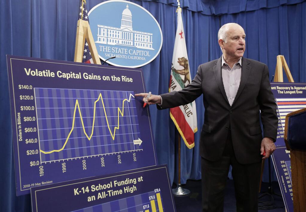 Gov. Jerry Brown gestures toward a chart showing the volatility of capital gains revenue while discussing his revised 2018-19 state budget at a news conference on Friday in Sacramento. (RICH PEDRONCELLI / Associated Press)