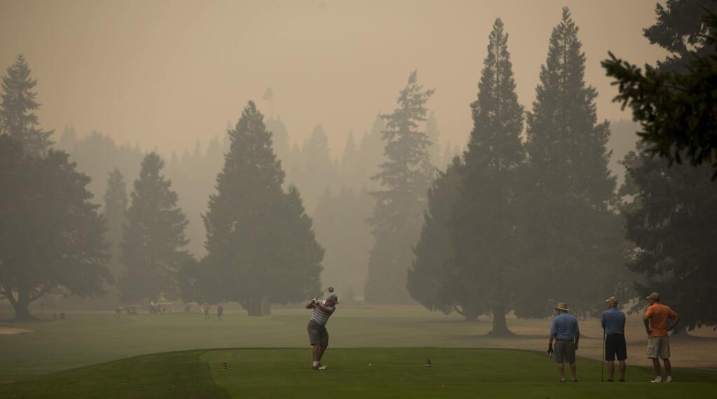 A golfer at Tokatee Golf Course tees off in smokey conditions at the facility near Rainbow, Ore., Wednesday, Sept. 6, 2017. (Andy Nelson/The Register-Guard via AP)