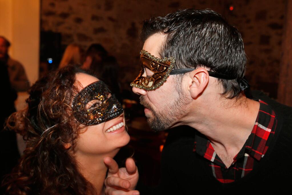 Greg Carl, right, leans in to kiss Angela Garcia during the Healdsburg Active 20-30 Club's Vignettes masquerade ball and fundraiser at Trione Vineyards and Winery in Geyserville, California on Saturday, February 18, 2017. (Alvin Jornada / The Press Democrat)