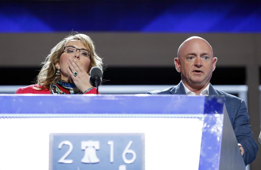 Former Rep. Gabby Giffords, D-Ariz, blows a kiss from the podium as her husband Astronaut Mark Kelly (ret.) looks on during a sound check before the start of the first day session of the Democratic National Convention in Philadelphia, Monday, July 25, 2016. (AP Photo/Carolyn Kaster)