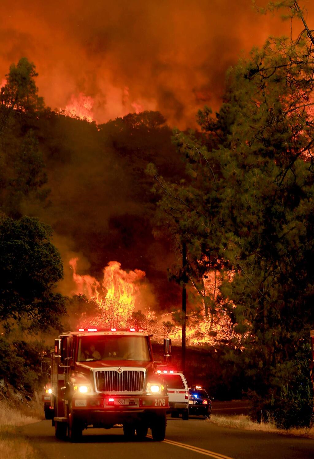 Fire personnel pull back from a wall of flames as it jumps Butts Canyon Road and Snell Valley Road, Tuesday, July 1, 2014 outside of Middletown. (Kent Porter / Press Democrat) 2014