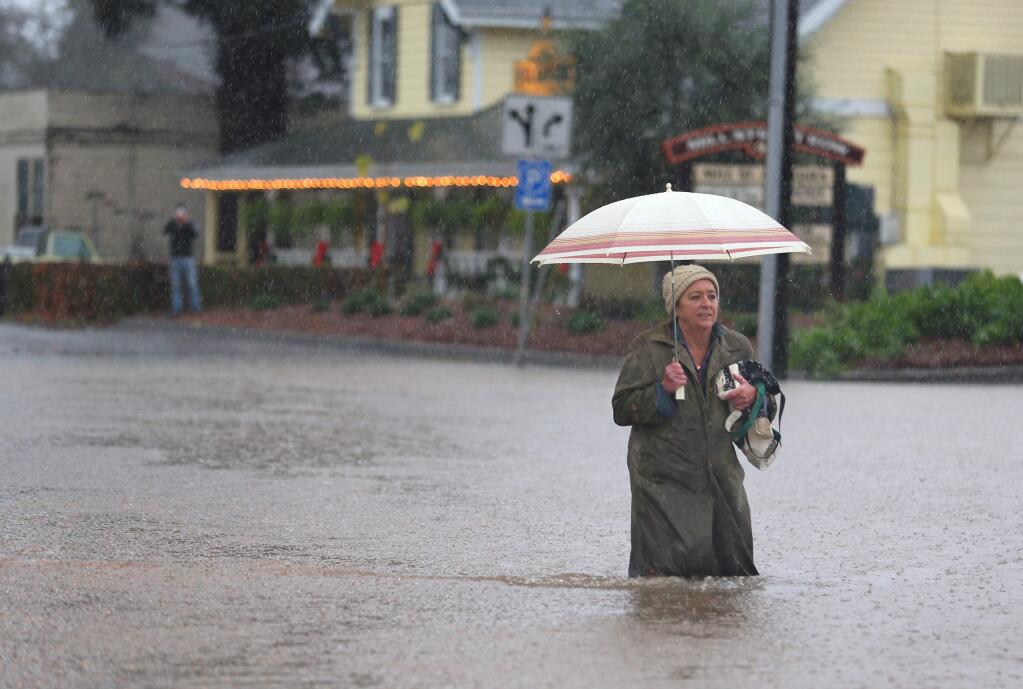 Beatrice Clark walks along the flooded Mill Street, at Westside Road, in Healdsburg on Thursday, Dec. 11, 2014. (CHRISTOPHER CHUNG/PD)