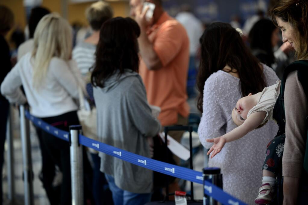 Ann Walden and her 15 month-old daughter Delphine wait in-line after their flight to Baton Rouge was delayed at O'Hare International Airport in Chicago, Friday, Sept. 26, 2014. (AP Photo/Paul Beaty)