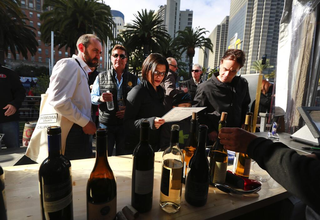 Patrons look through a list of wines to sample at the Sonoma County wine and tourism tent in San Francisco's Super Bowl City. (JOHN BURGESS / The Press Democrat)
