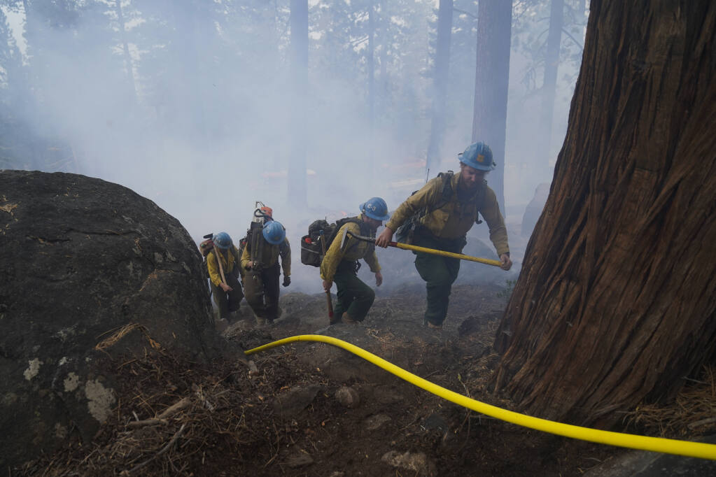 Members of a hotshot crew hike up the mountain while battling the Caldor Fire in South Lake Tahoe, Calif., Friday, Sept. 3, 2021. Fire crews took advantage of decreasing winds to battle a California wildfire near popular Lake Tahoe and were even able to allow some people back to their homes but dry weather and a weekend warming trend meant the battle was far from over. (AP Photo/Jae C. Hong)