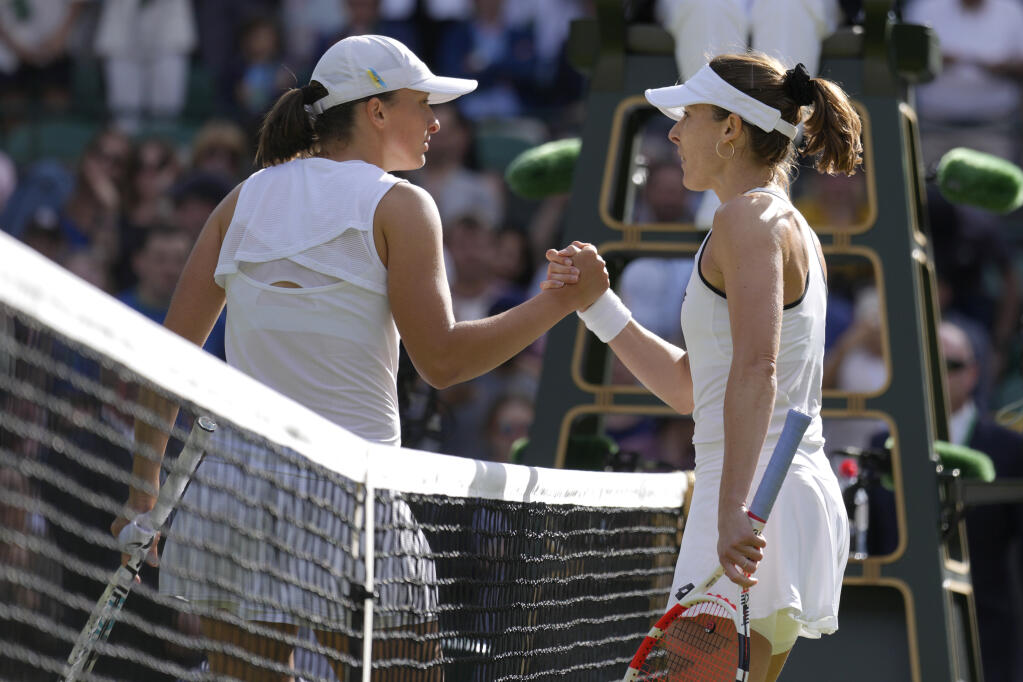 Iga Swiatek, left, shakes hands with Alize Cornet after Cornet defeated her in the third round at Wimbledon in London on Saturday, July 2, 2022. (Kirsty Wigglesworth / ASSOCIATED PRESS)