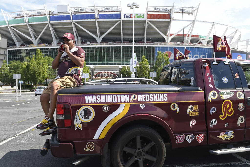Rodney Johnson of Chesapeake, Va., sits on the back of his truck outside FedEx Field in Landover, Md., Monday, July 13, 2020. The Washington NFL franchise announced Monday that it will drop the "Redskins" name and Indian head logo immediately, bowing to decades of criticism that they are offensive to Native Americans. (AP Photo/Susan Walsh)