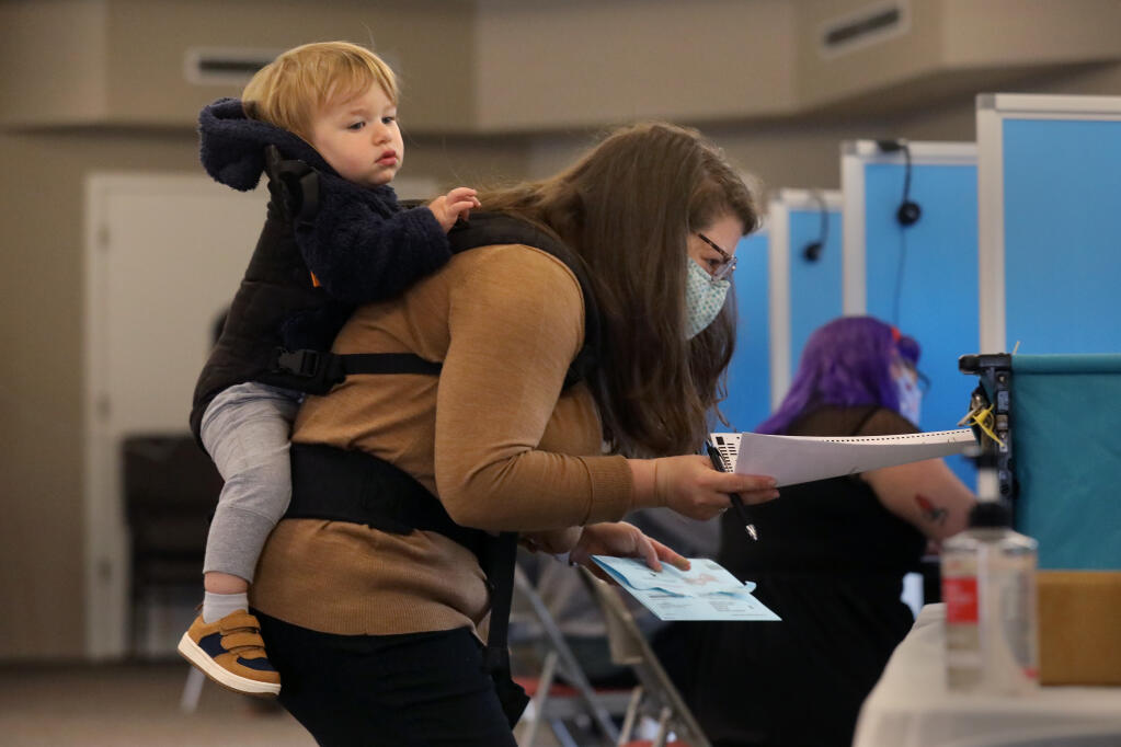 Elisette Weiss, joined by her son, Judah Bockelweiss, 1,  tries to cast her ballot at the polling location at Christ Church United Methodist in Santa Rosa, Calif., on Tuesday, Nov. 3, 2020.  (Beth Schlanker / The Press Democrat)