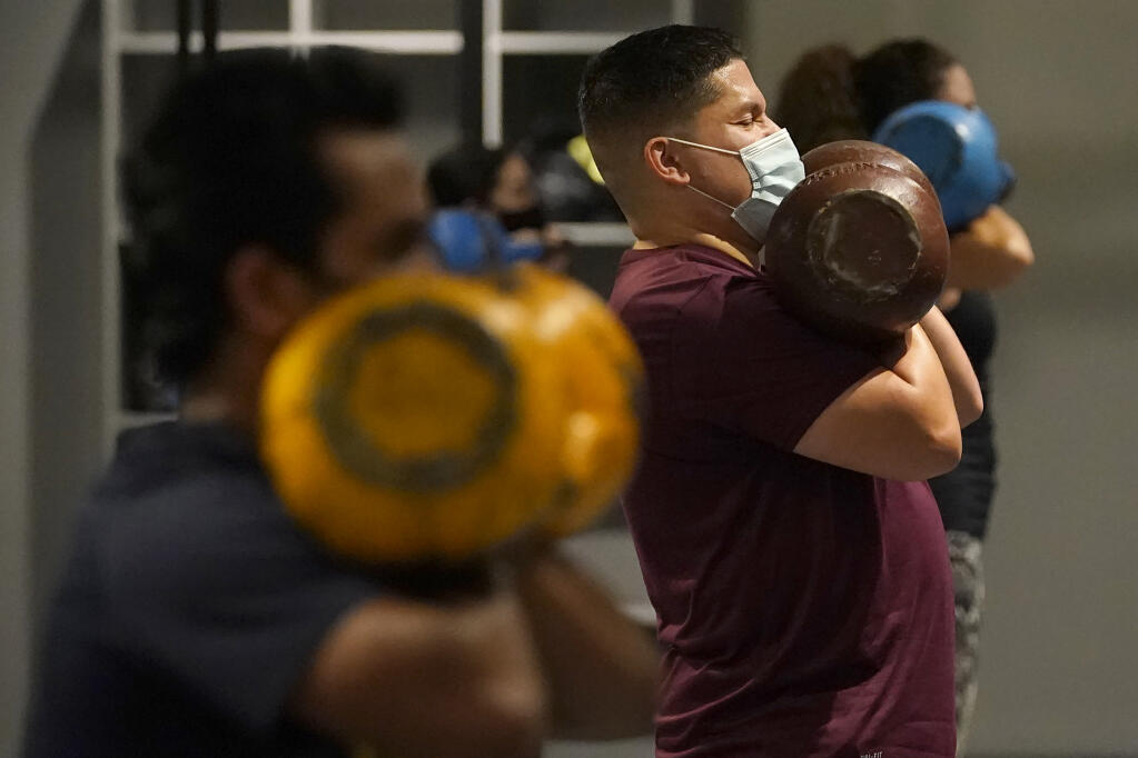 Juan Avellan, center, and others wear masks while working out in an indoor class at a Hit Fit SF gym amid the coronavirus outbreak in San Francisco, Tuesday, Nov. 24, 2020. (AP Photo/Jeff Chiu)