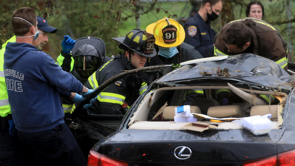 Rescue personnel from American Medical Response,  Rancho Adobe Fire District, Sonoma County Fire District and Rohnert Park Department of Public Safety extricate victims of a rollover along Petaluma Hill Road, Thursday, March 18, 2021.  (Kent Porter / The Press Democrat) 2021